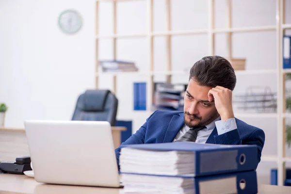 Jovem funcionário masculino e muito trabalho no escritório — Fotografia de Stock