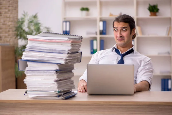 Young male employee and a lot of work in the office — Stock Photo, Image