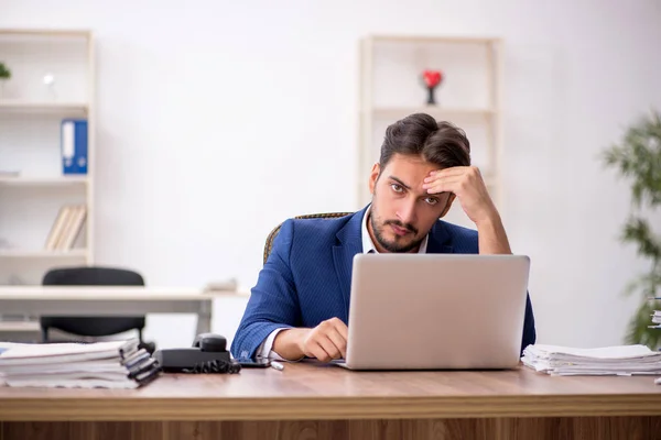 Joven empleado masculino descontento con el trabajo excesivo en la oficina — Foto de Stock