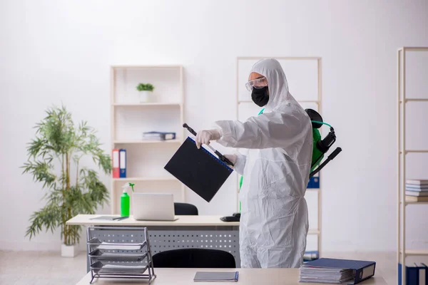 Young male contractor disinfecting office during pandemic — Stok fotoğraf