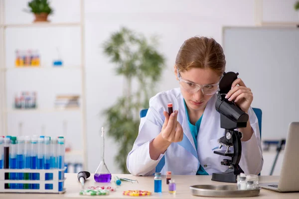 Joven química femenina en concepto de síntesis de fármacos —  Fotos de Stock