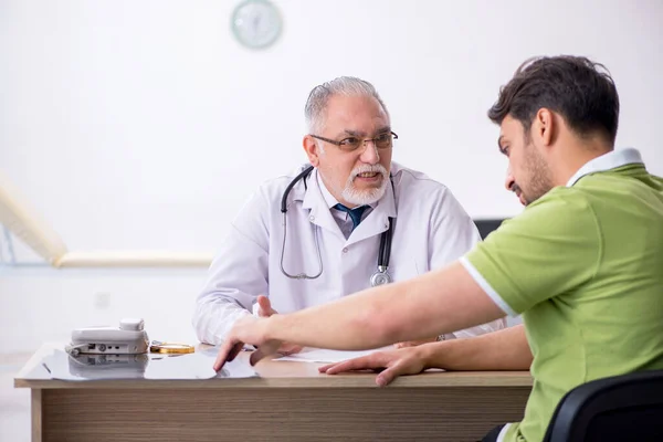 Young man visiting old male doctor — Stock Photo, Image