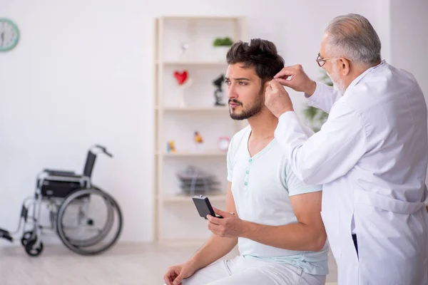 Jeune patient de sexe masculin avec un problème auditif visite vieux médecin otor — Photo