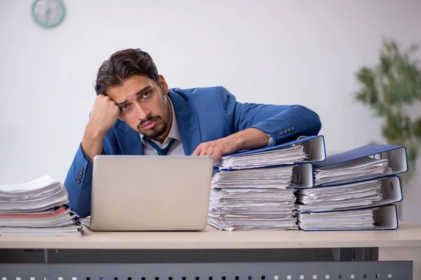 Jovem funcionário masculino e muito trabalho no escritório — Fotografia de Stock