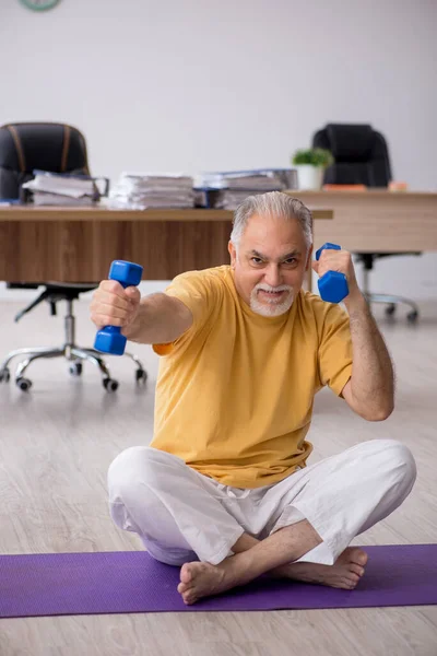 Oude zakenman werknemer doet sport oefeningen in het kantoor — Stockfoto