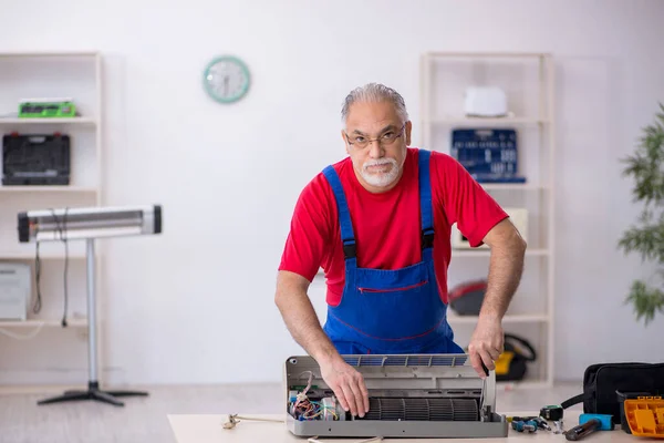 Starý opravář opravující klimatizaci v dílně — Stock fotografie