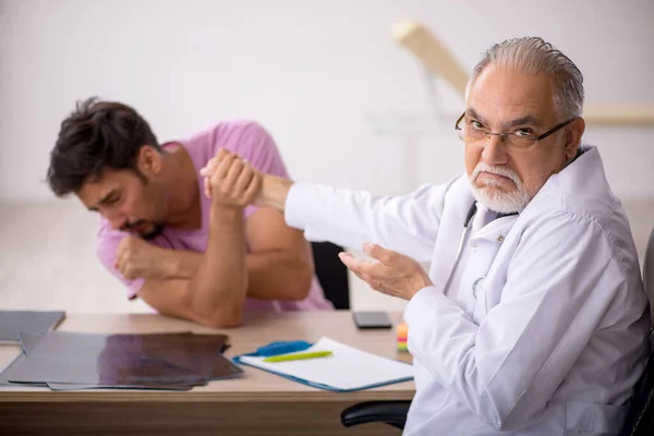 Ung manlig patient besöker gamla manliga läkare — Stockfoto