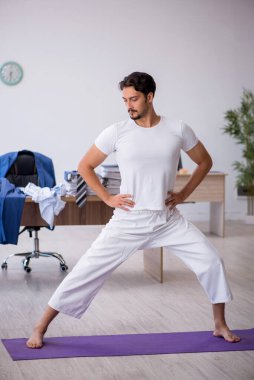 Genç erkek çalışan ofiste spor egzersizleri yapıyor.