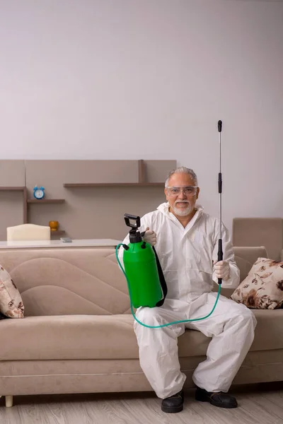 Old male contractor doing pest control at home — Stock Photo, Image