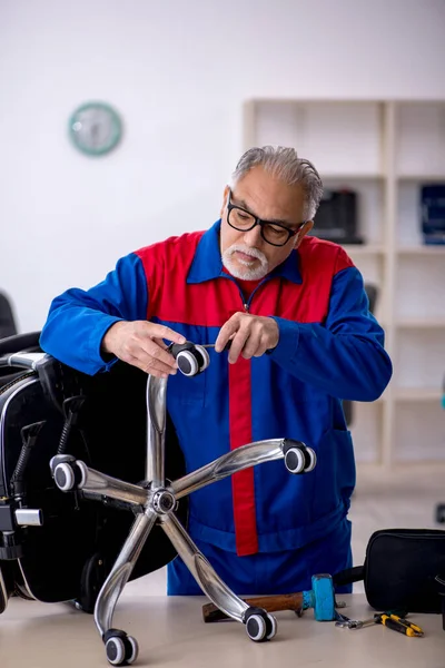 Oude mannelijke reparateur repareert bureaustoel — Stockfoto