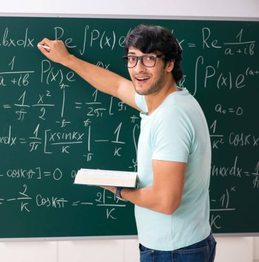 Kara tahta önünde genç erkek öğrenci matematikçi