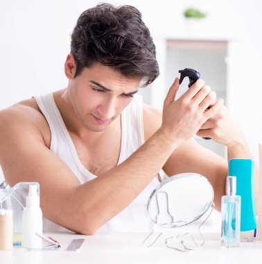 Genç yakışıklı adam aynaya bakıyor.