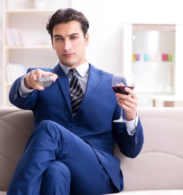 İş adamı evde oturmuş şarap içiyor.