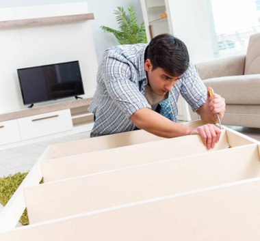 Adam evde mobilya montajı yapıyor.