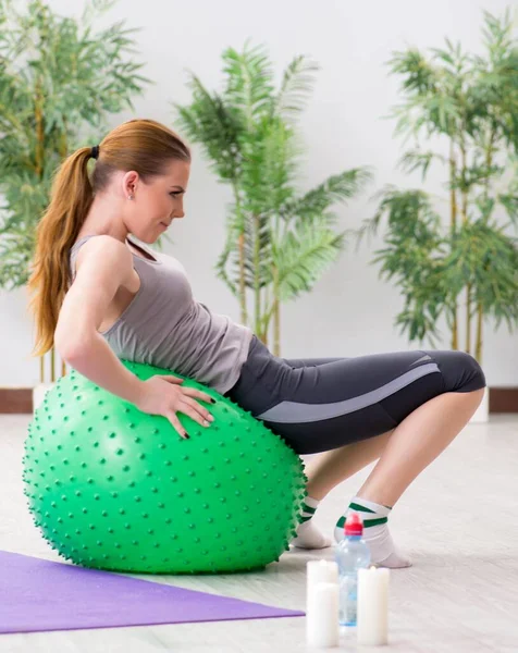 Spor salonunda denge topuyla egzersiz yapan genç bir kadın. — Stok fotoğraf