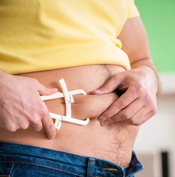 Homem jovem medindo gordura corporal com paquímetros — Fotografia de Stock
