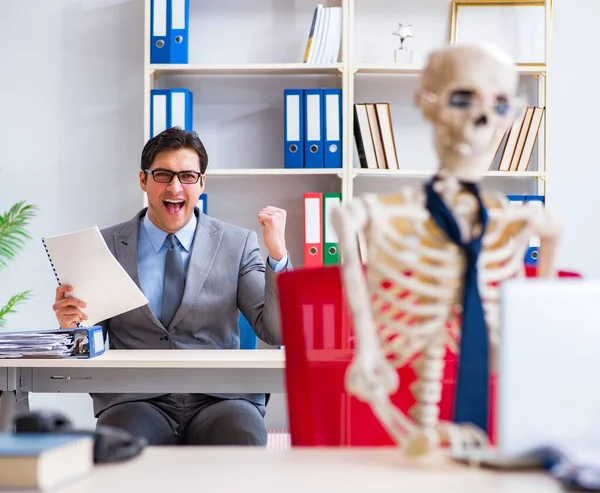 Biznesmen pracujący ze szkieletem w biurze — Zdjęcie stockowe