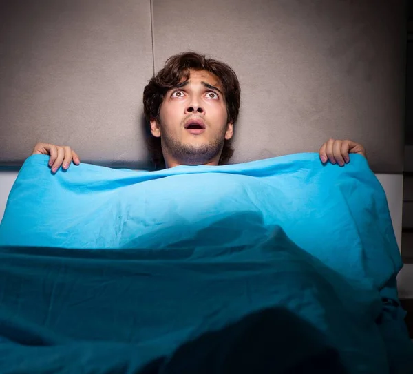 Giovane uomo spaventato nel suo letto avendo incubi — Foto Stock