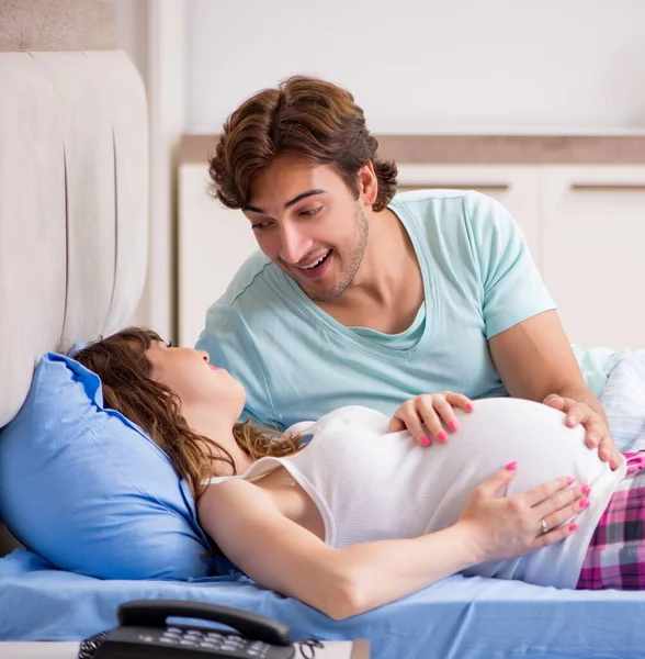 Zwangere vrouw met echtgenoot in de slaapkamer — Stockfoto