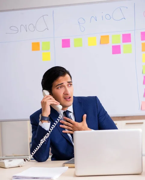 Young handsome employee in front of whiteboard with to-do list — Stock Photo, Image