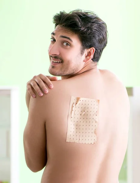 Mężczyzna nakłada plaster pieprzowy Capsicum łagodzić ból — Zdjęcie stockowe