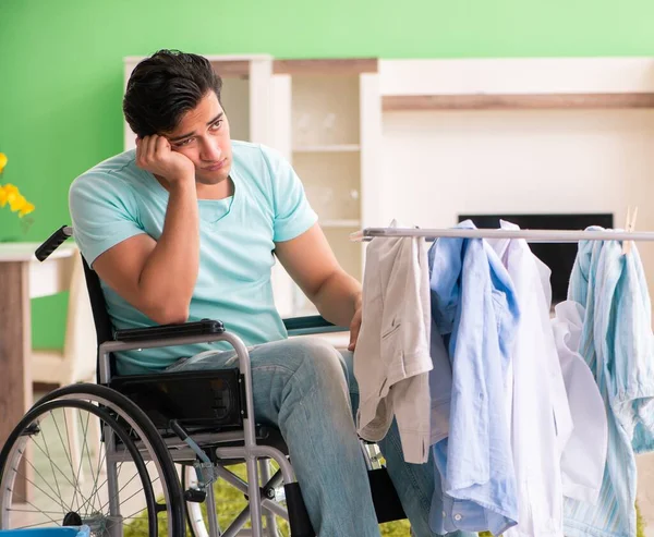 Uomo disabile sulla sedia a rotelle che fa il bucato — Foto Stock