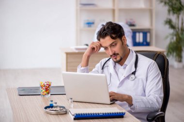 Klinikte çalışan genç erkek doktor.