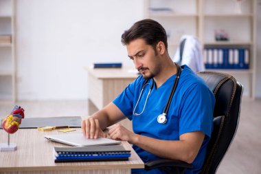 Klinikte çalışan genç erkek doktor.