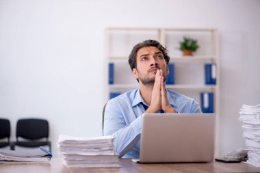 Genç bir erkek çalışan ve ofiste çok fazla iş var.