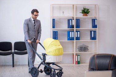 Genç erkek çalışan işyerinde yeni doğan çocuğa bakıyor.