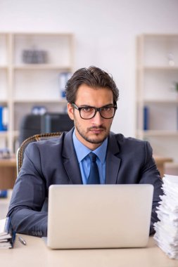 Genç bir erkek çalışan ve ofiste çok fazla iş var.