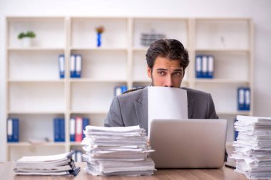 Genç bir erkek çalışan ve ofiste çok fazla iş var.