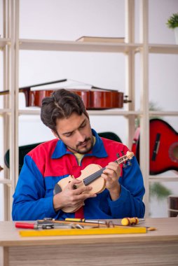 Genç adam atölyede müzik aletlerini tamir ediyor.