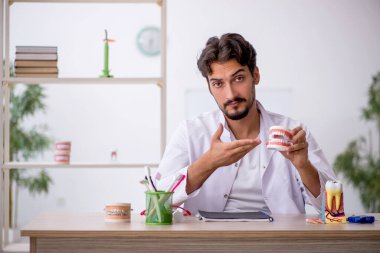 Klinikte çalışan genç erkek dişçi.