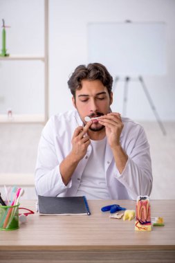 Klinikte çalışan genç erkek dişçi.