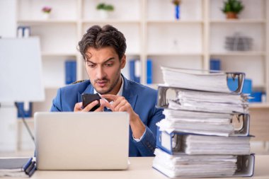 Genç bir erkek çalışan ve ofiste çok fazla iş var.