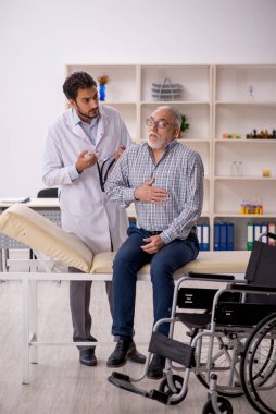 Tekerlekli sandalyedeki yaşlı adam genç erkek doktoru ziyaret ediyor.