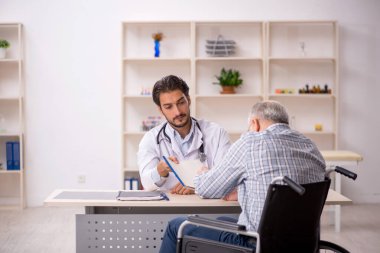 Tekerlekli sandalyedeki yaşlı adam genç erkek doktoru ziyaret ediyor.