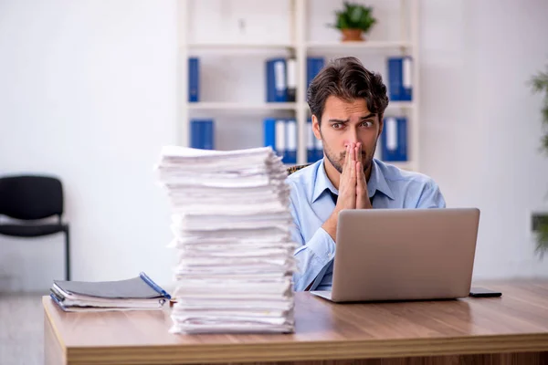 Joven empleado masculino y demasiado trabajo en la oficina — Foto de Stock