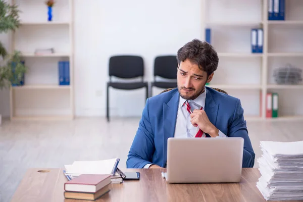 Joven empleado masculino y demasiado trabajo en la oficina — Foto de Stock