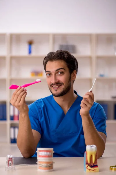 Jonge mannelijke tandarts werkzaam in de kliniek — Stockfoto