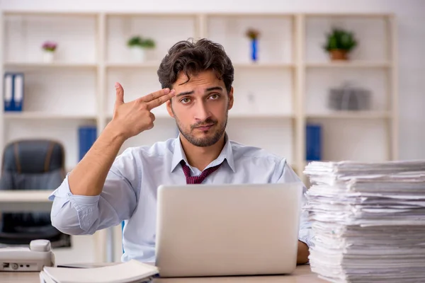 Ung manlig anställd och för mycket arbete på kontoret — Stockfoto