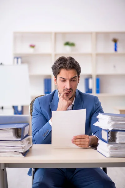 Ung manlig anställd och för mycket arbete på kontoret — Stockfoto