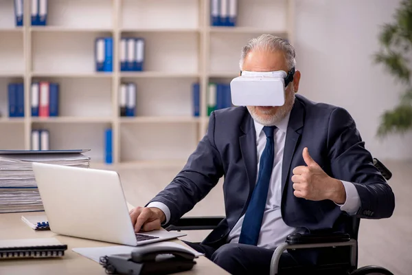Alter am Bein verletzter männlicher Angestellter mit virtueller Brille am Arbeitsplatz — Stockfoto