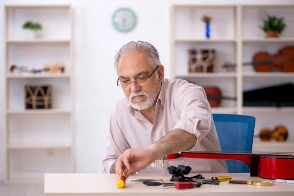 Yaşlı erkek tamirci atölyede müzik aletlerini tamir ediyor. — Stok fotoğraf
