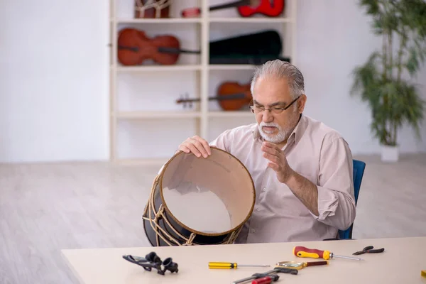 Homem velho reparador reparando instrumentos musicais na oficina — Fotografia de Stock