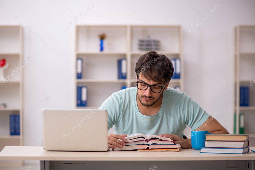 Young male student preparing for exams in the classroom