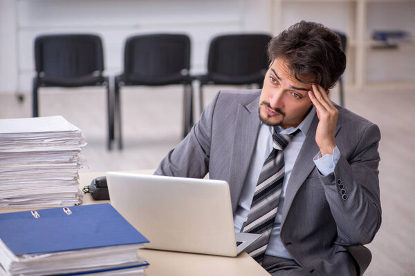 Молодой бизнесмен и слишком много работы в офисе
