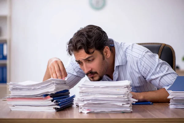 Jovem funcionário masculino e muito trabalho no escritório — Fotografia de Stock