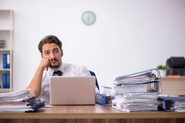 Joven empleado masculino y demasiado trabajo en la oficina — Foto de Stock